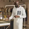 Pristine white kaftan with gold pinstripes, accented by a contrasting navy blue chest pocket.