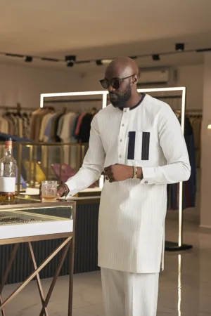 Pristine white kaftan with gold pinstripes, accented by a contrasting navy blue chest pocket.