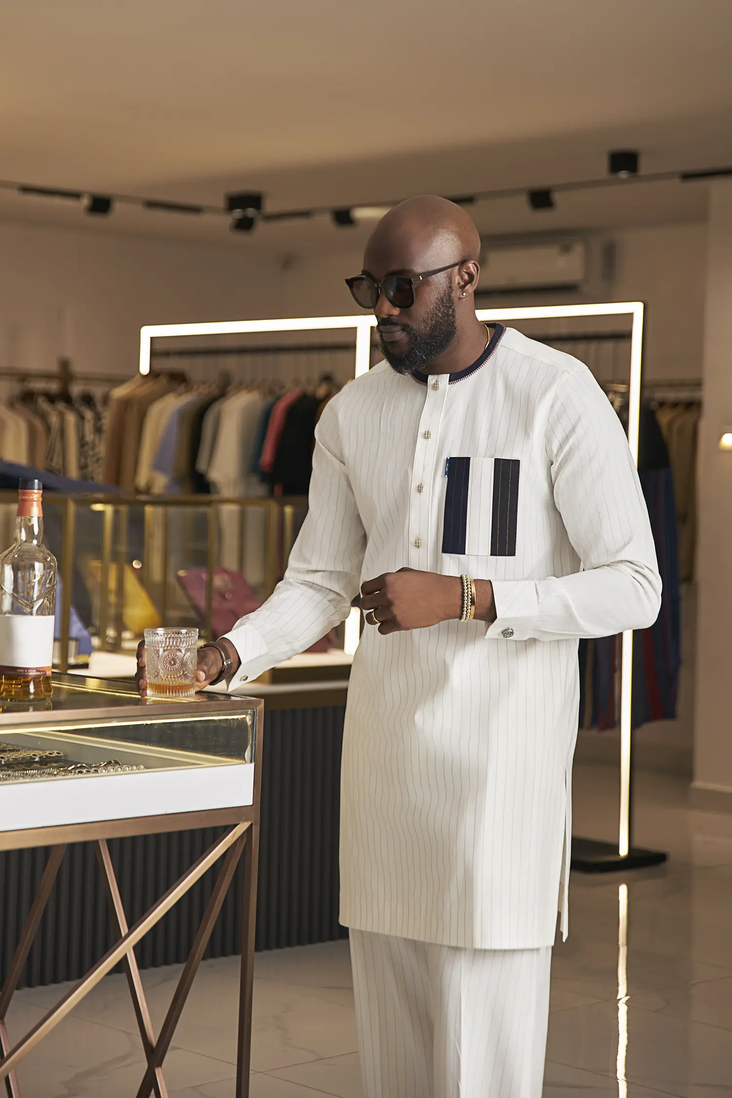 Pristine white kaftan with gold pinstripes, accented by a contrasting navy blue chest pocket.